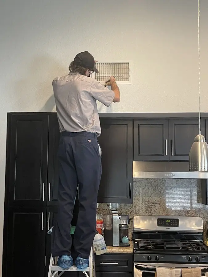 Technician inspecting an air vent during HVAC service in Traverse City